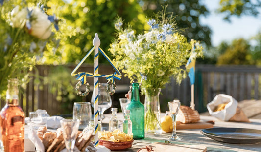 A table outside in sunny weather laden with food and mismatched tableware, for an informal summer gathering