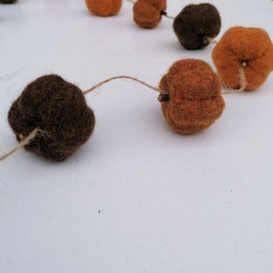 Close up of the felted brown and orange pumpkins on a white background