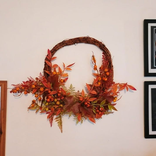 Decorative wreath with autumn leaves and berries on a wall.