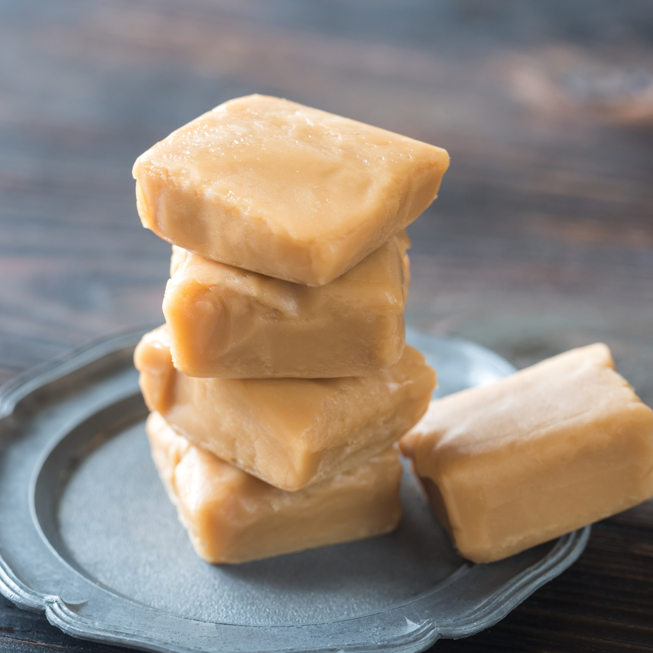 Stack of fudge squares on a metal plate with a blurred wooden background
