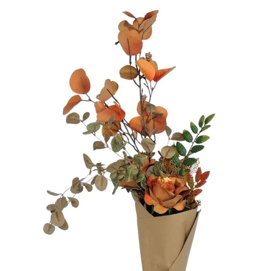 Close up of Artificial flower arrangement with orange and green leaves in a brown paper cone on a white background