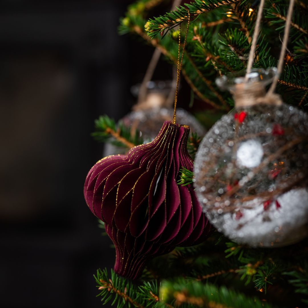 Decorative Christmas ornaments hanging on a tree branch with a dark background