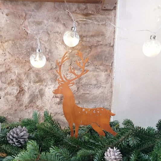 Rusty metal stag standing in a pile of fir foliage with cones