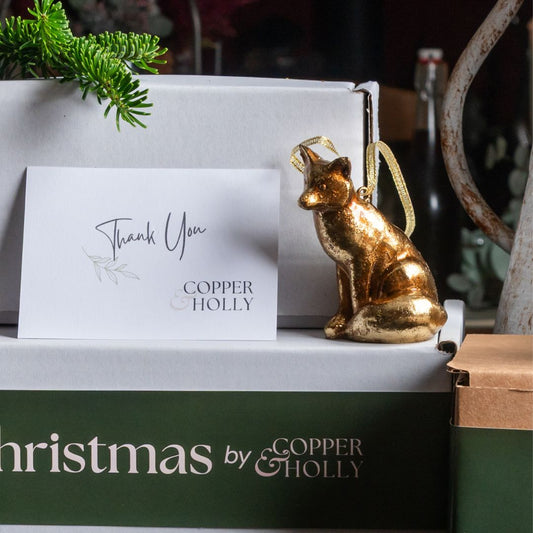 Gold fox ornament on a 'Christmas by Copper & Holly' box with a 'Thank You' card.