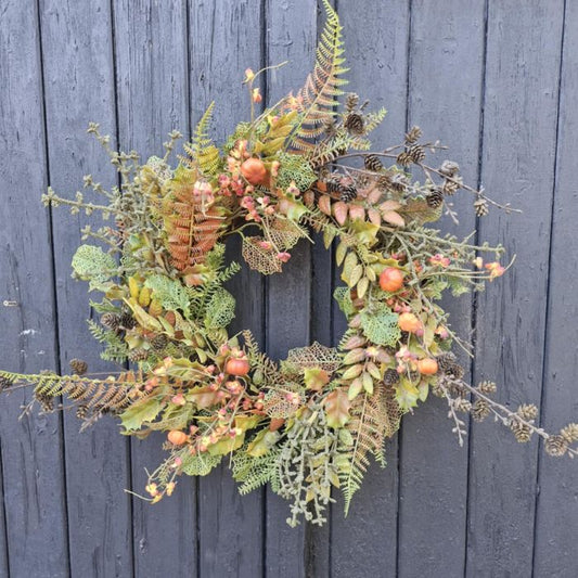 Decorative wreath with greenery and fruits against a dark wooden background
