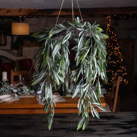 Hanging green leafy wreath in a dimly lit room with a table and decorative lights.