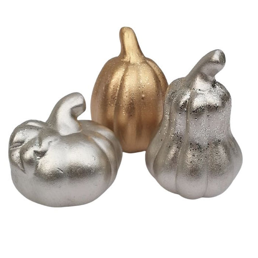 Three decorative pumpkins in gold and silver on a white background