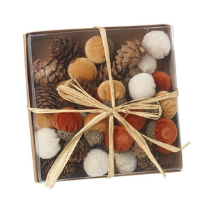Box tied with hessian string, containing velvet acorns in oranges and whites, along with small pinecones