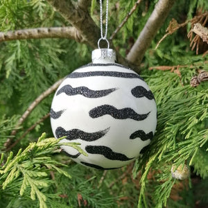 Showing the bauble shaped animal print Christmas bauble against a tree background