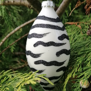 Showing the olive shape animal print Christmas bauble against a tree background