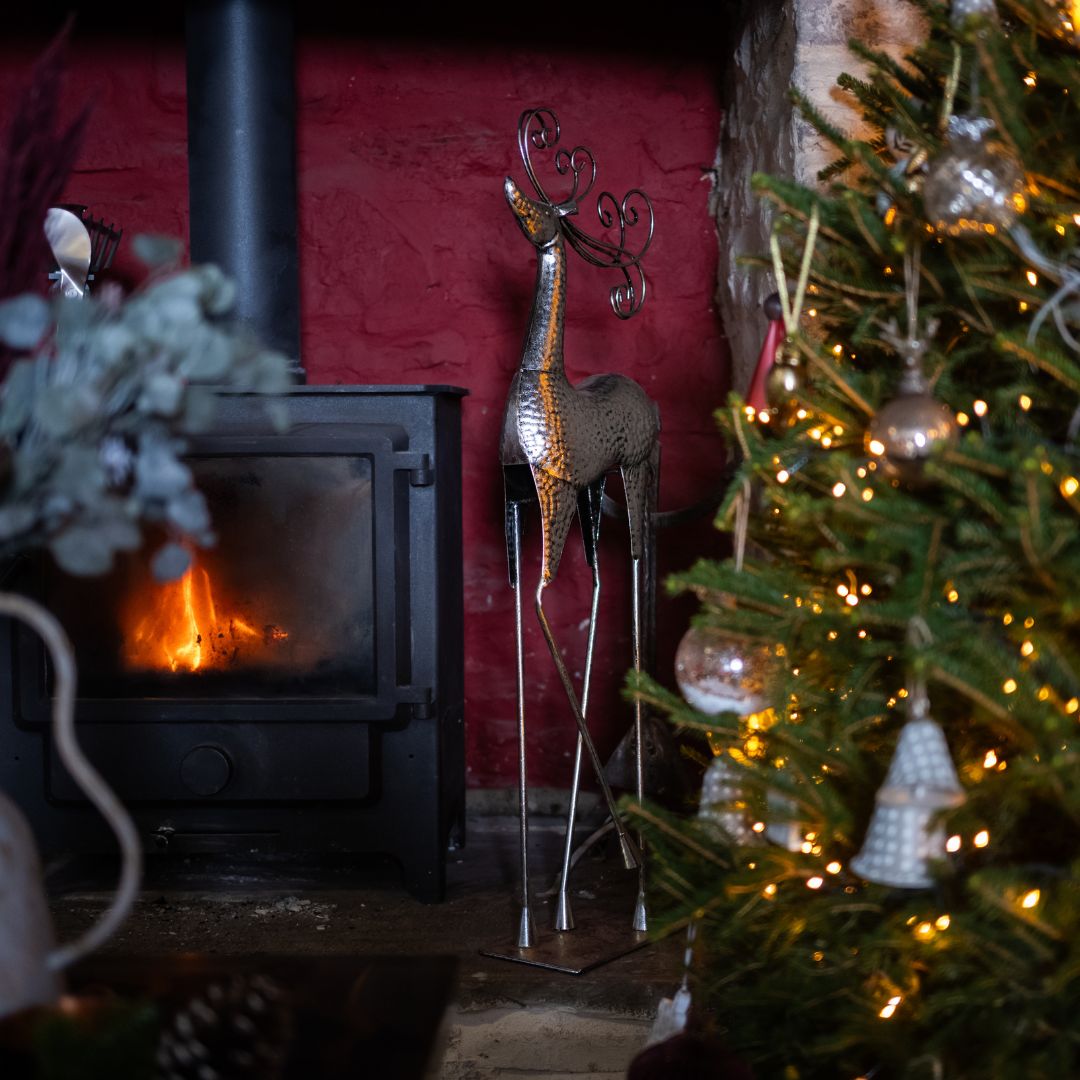 Cozy indoor scene with a fireplace, Christmas tree, and decorative deer.