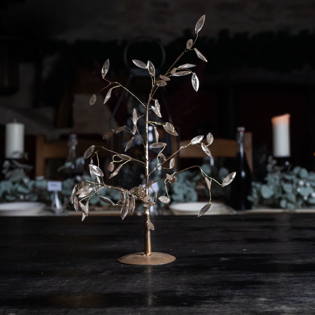 Rose gold metal and bead tree against a dimly lit background