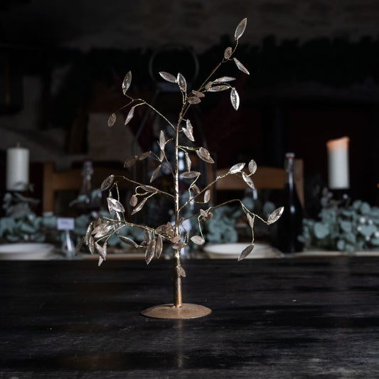Rose gold metal and bead tree against a dimly lit background