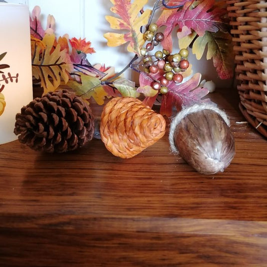 Decorative arrangement with pinecones, a nut, and autumn leaves on a wooden surface.