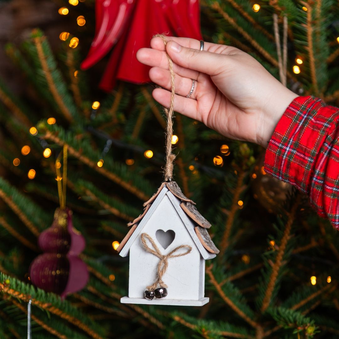 A birdhouse hanging decoration against a Christmas tree