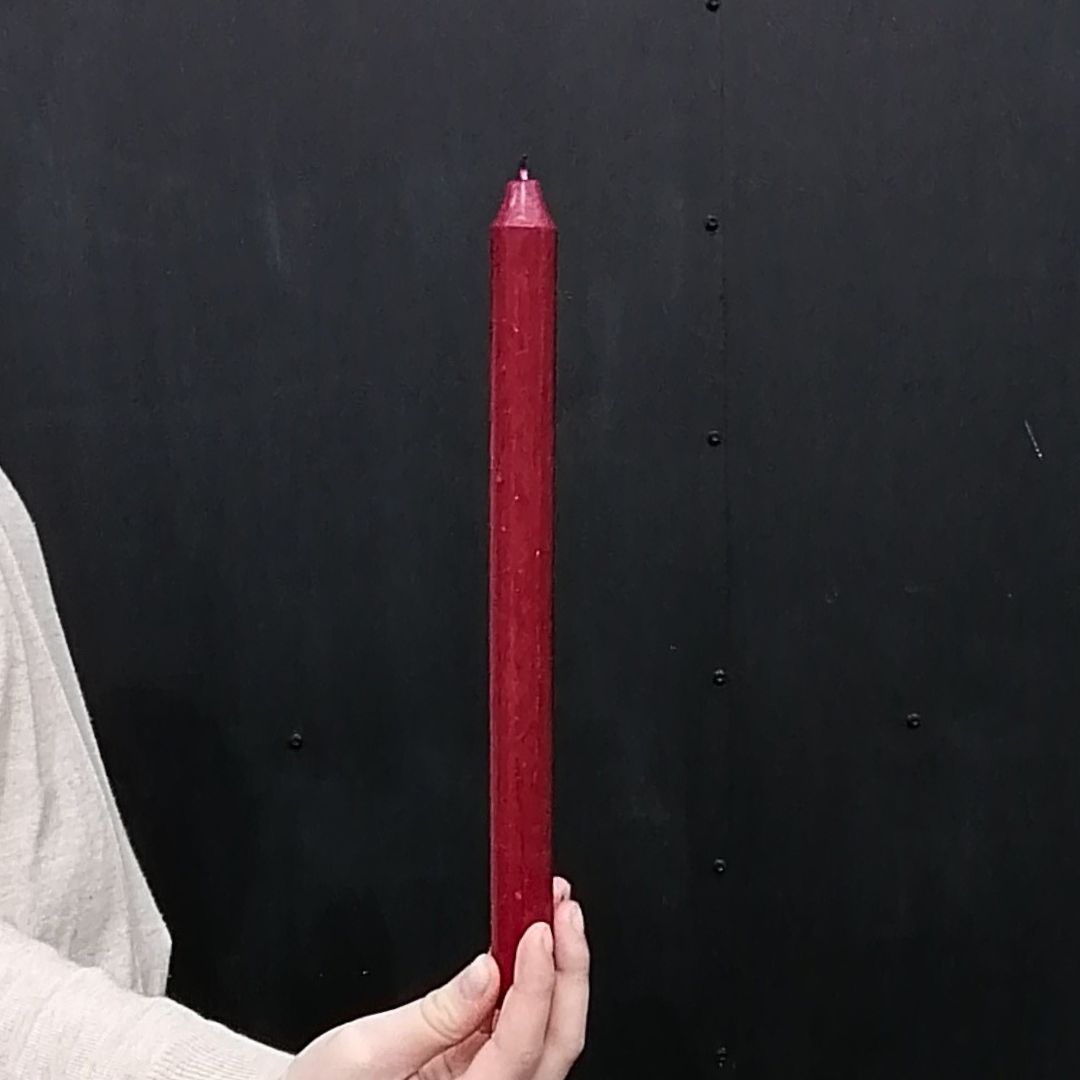 Image showing burgundy fragrance free wax dinner candle in model's hand to show scale
