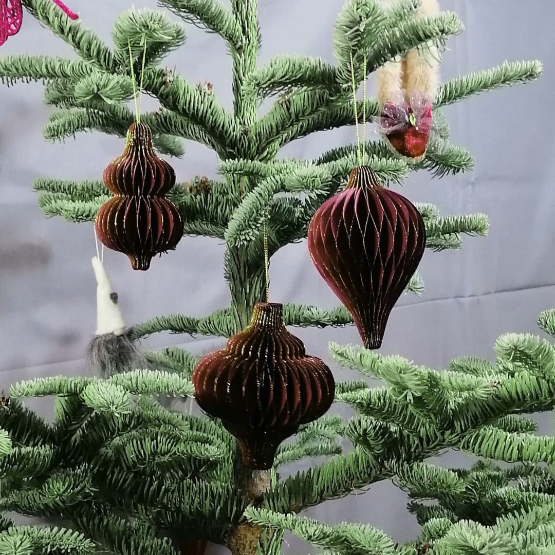 Showing the 3 different styles of burgundy honeycomb paper decorations on a Christmas tree with a dark grey background