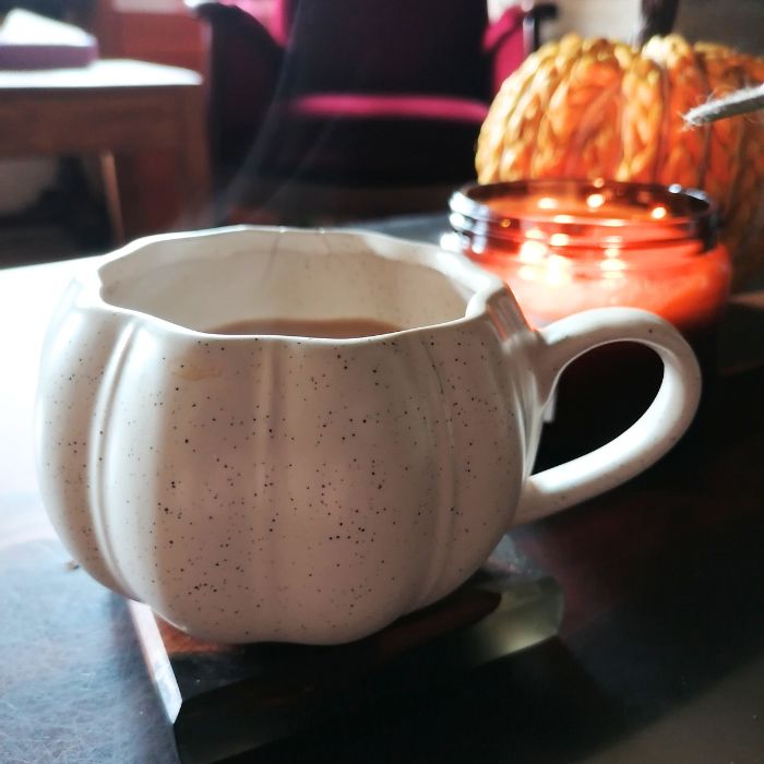 Speckled ceramic pumpkin mug on a table with a blurred background