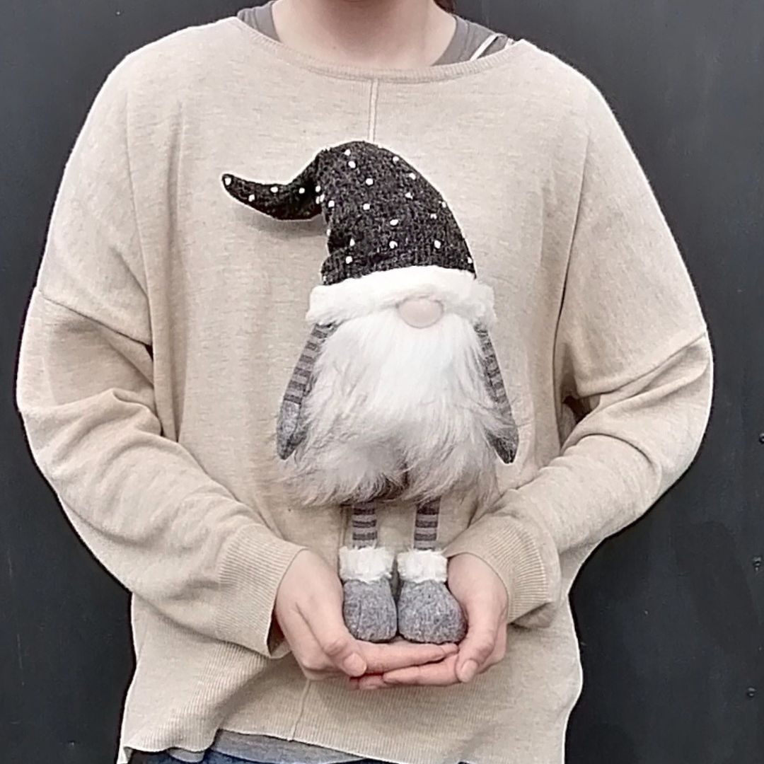 Charcoal grey spotty-hat fabric gonk in model's hands to show scale against a dark grey background