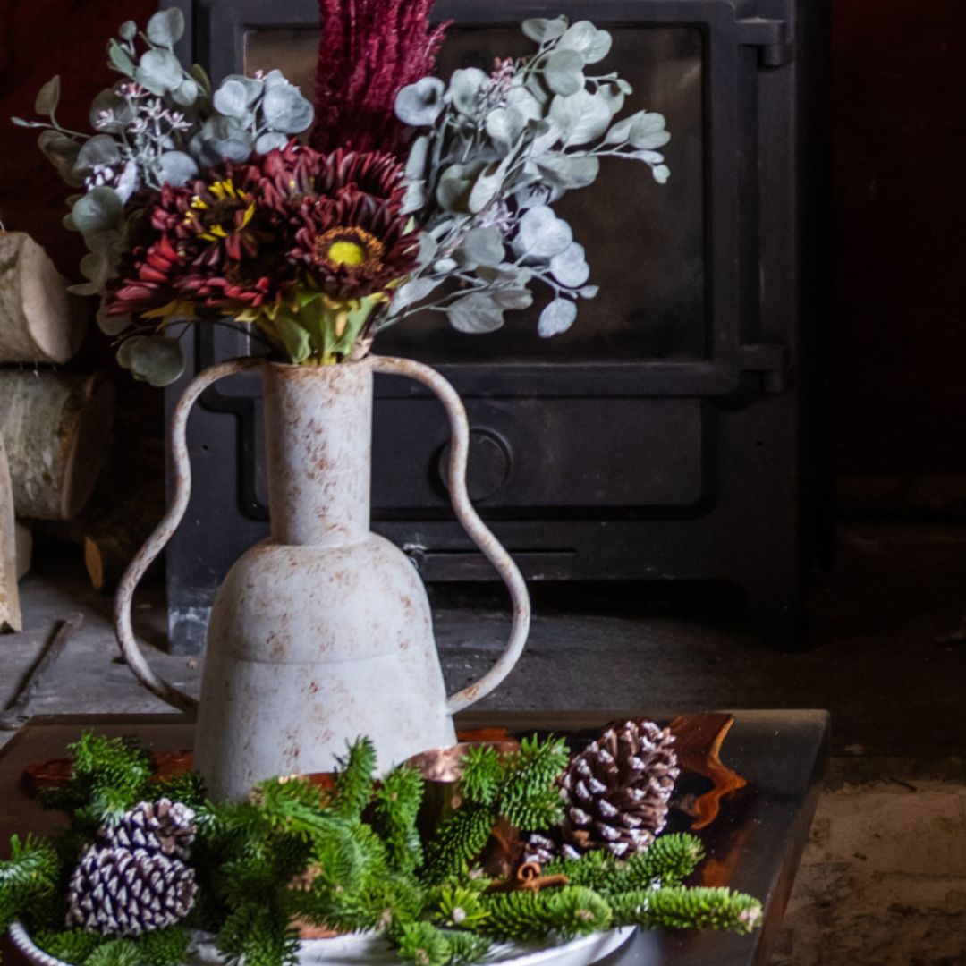 Decorative vase with flowers on a table in front of a fireplace