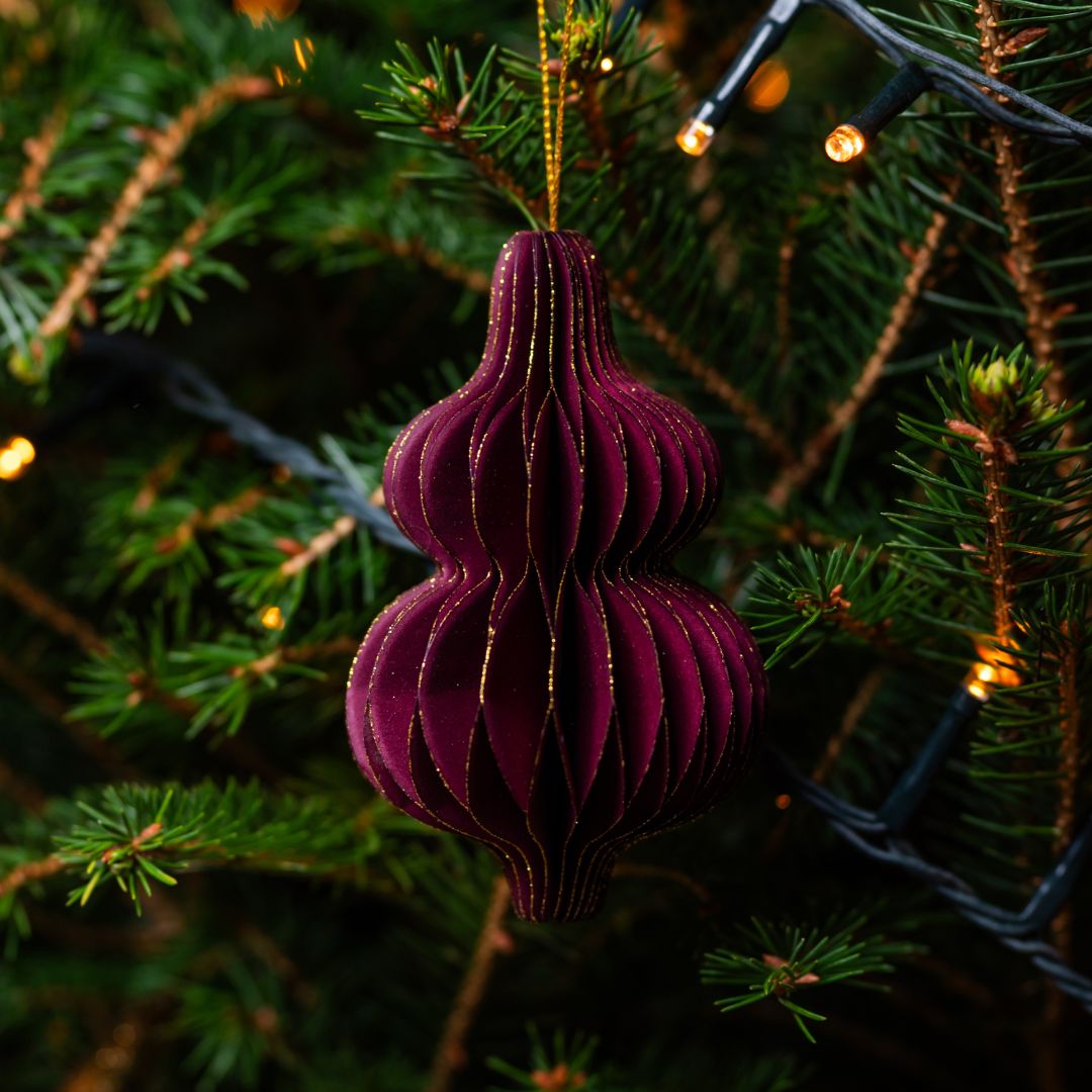 Burgundy decorative ornament on a Christmas tree with lights