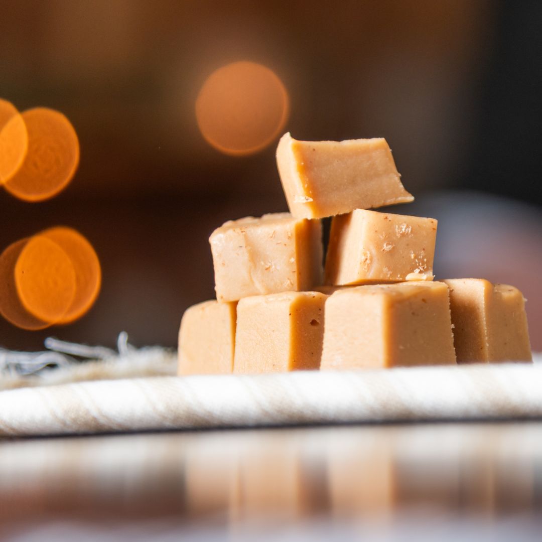 Stack of eggnog fudge pieces on a blurred background with warm tones