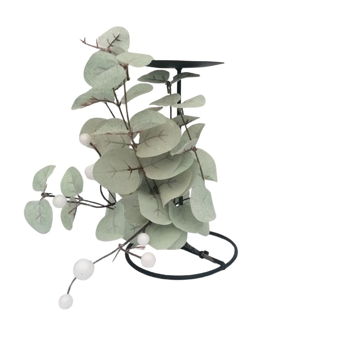 Decorative plant with green leaves and white berries on a black stand against a white background
