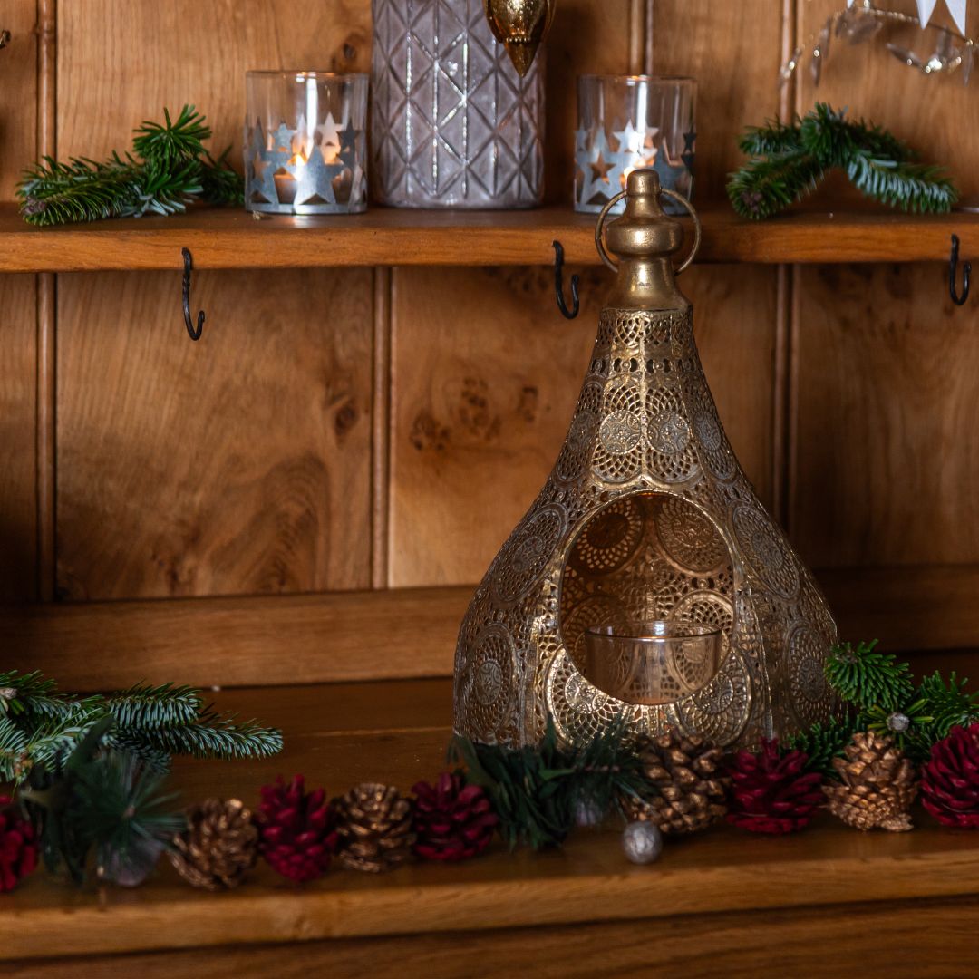 Decorative lantern on a wooden shelf with candles and greenery