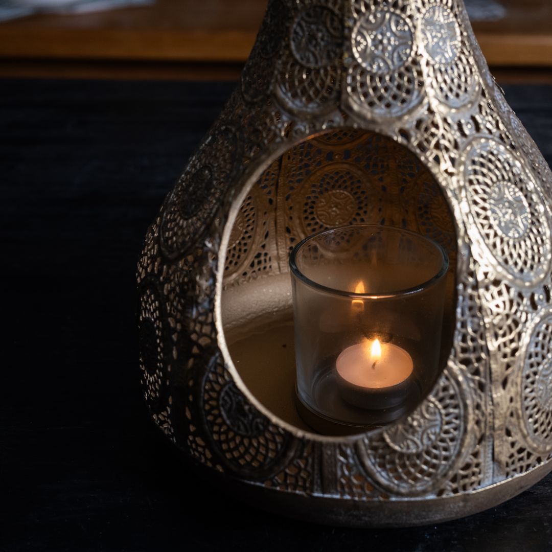 Decorative metal lantern with a candle inside on a dark background