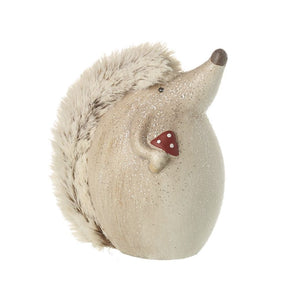 Handpainted hedgehog in neutral tones, with beige fur along his back, and this hedgehog decoration is holding a painted red and white toadstool in his paw