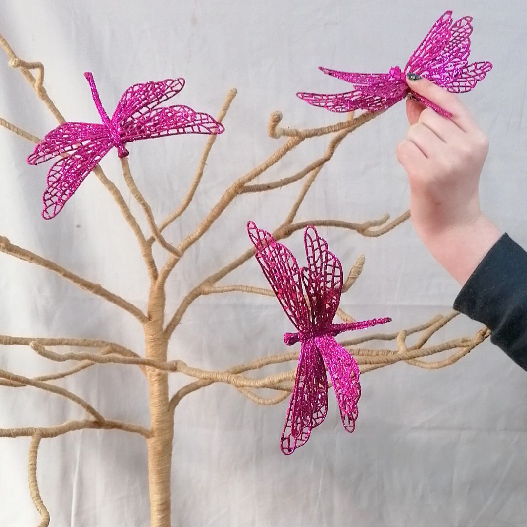 Image showing butterflies on a twig branch, including one in a models hands, showing scale of the hot pink glittered butterfly clip on decoration