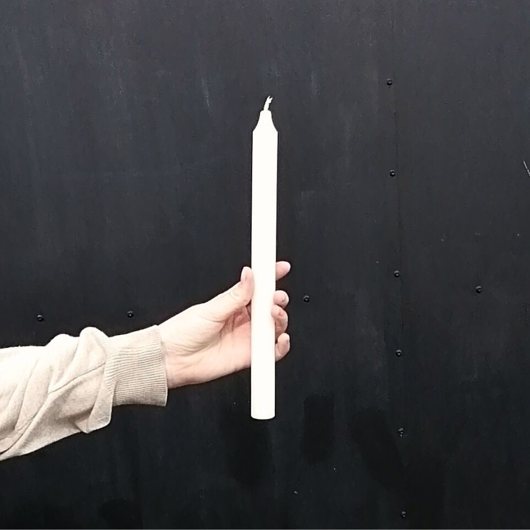 Ivory fragrance free wax dinner candle in model's hand showing size against a black background