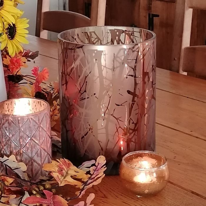 Decorative candles and lanterns on a wooden table with autumn-themed decor.
