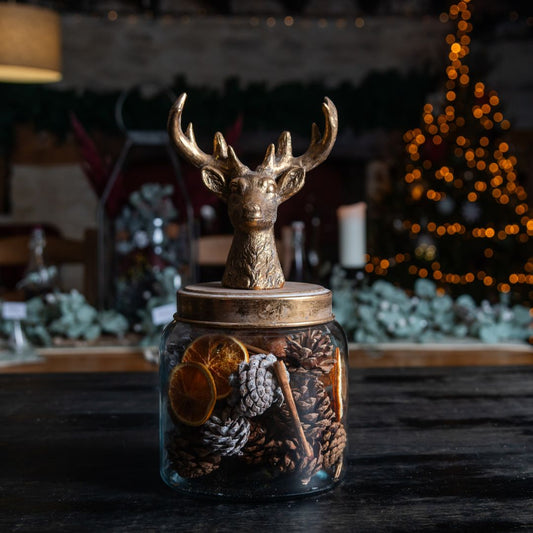 Decorative jar with a deer figure on top, surrounded by festive decorations.