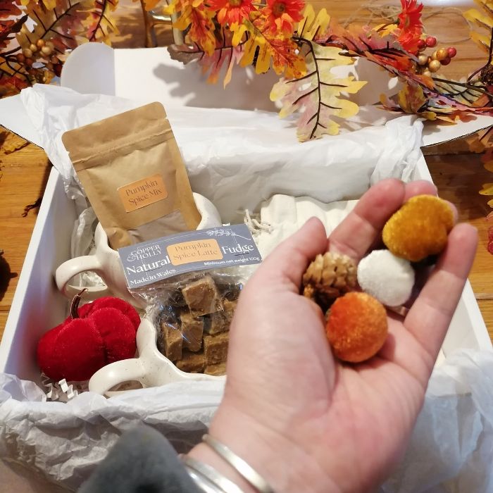 hand holding small velvet acorns with other autumnal items visible in box