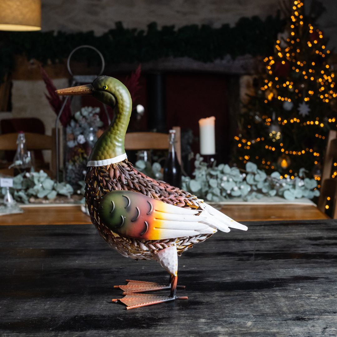 Decorative duck figure on a wooden surface with a festive background