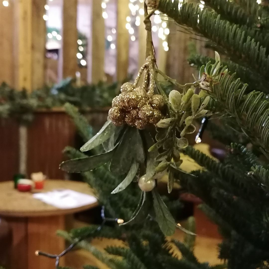 Decorative mistletoe with berries hanging on a Christmas tree.