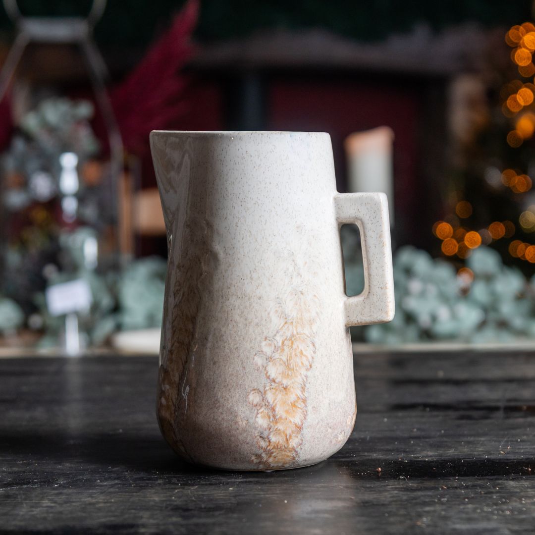 Ceramic pitcher on a dark surface with a blurred background