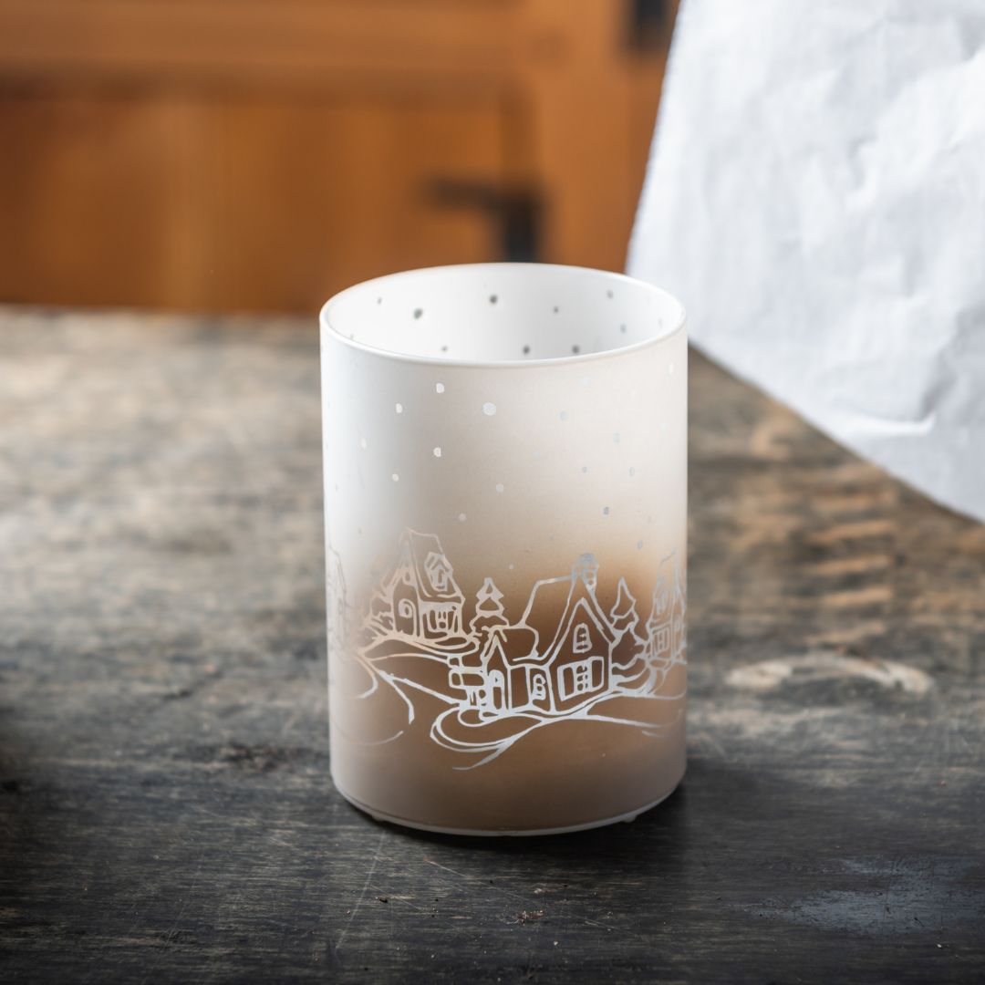 Frosted lights holder with a winter scene design on a wooden surface