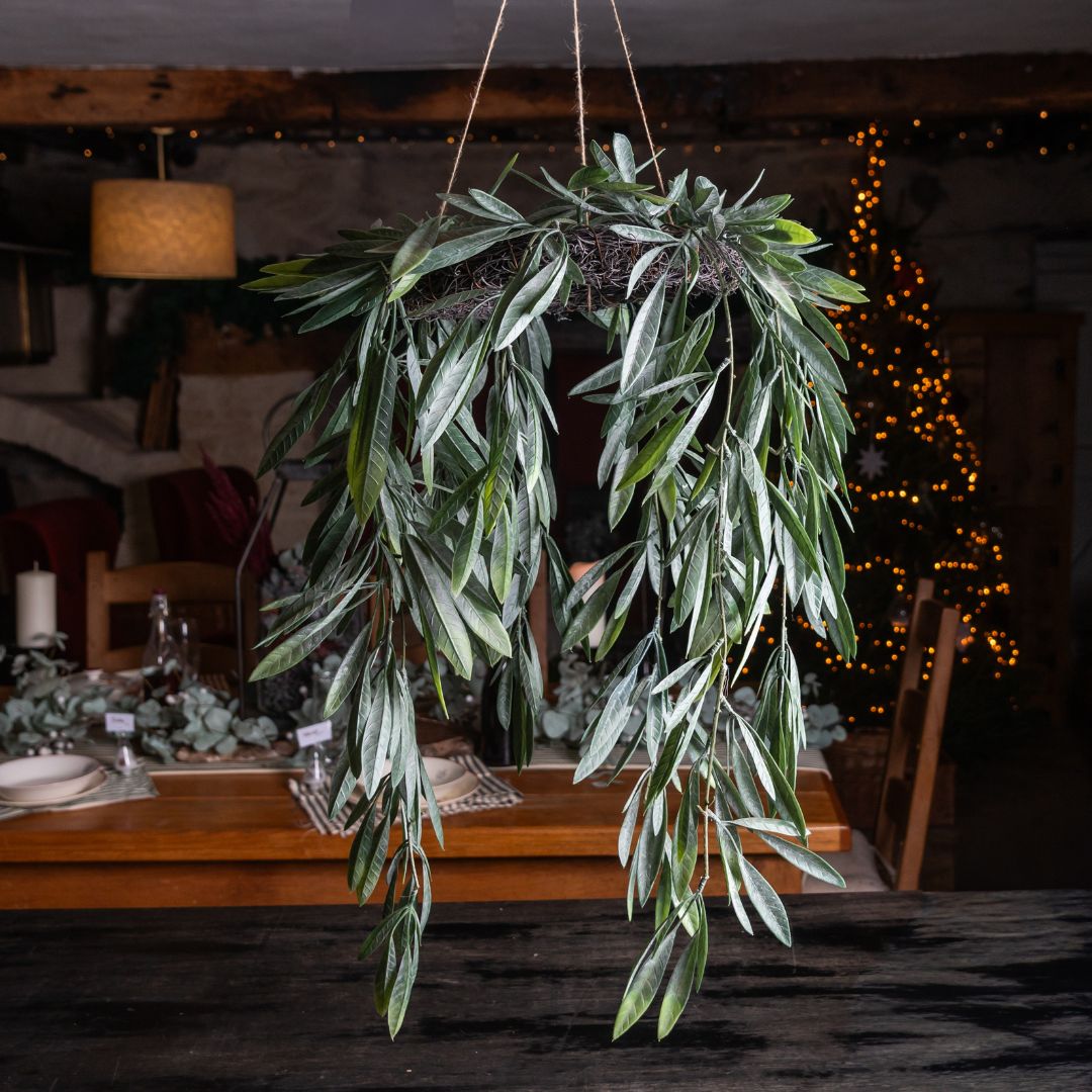 Hanging green leafy wreath in a dimly lit room with a table and decorative lights.