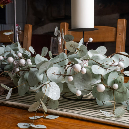 Decorative eucalyptus candle holder on a table with a garland