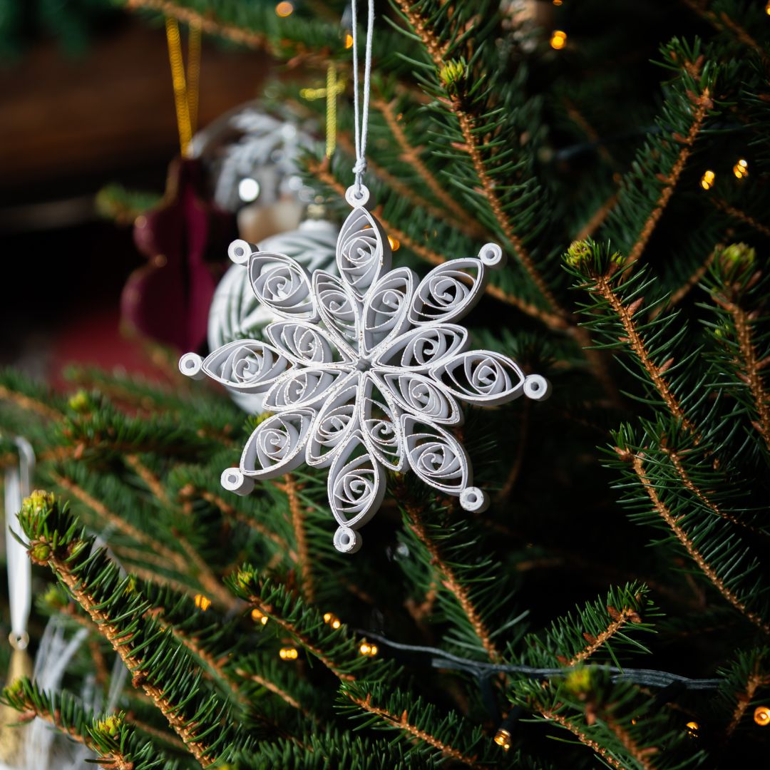 White snowflake ornament hanging on a Christmas tree