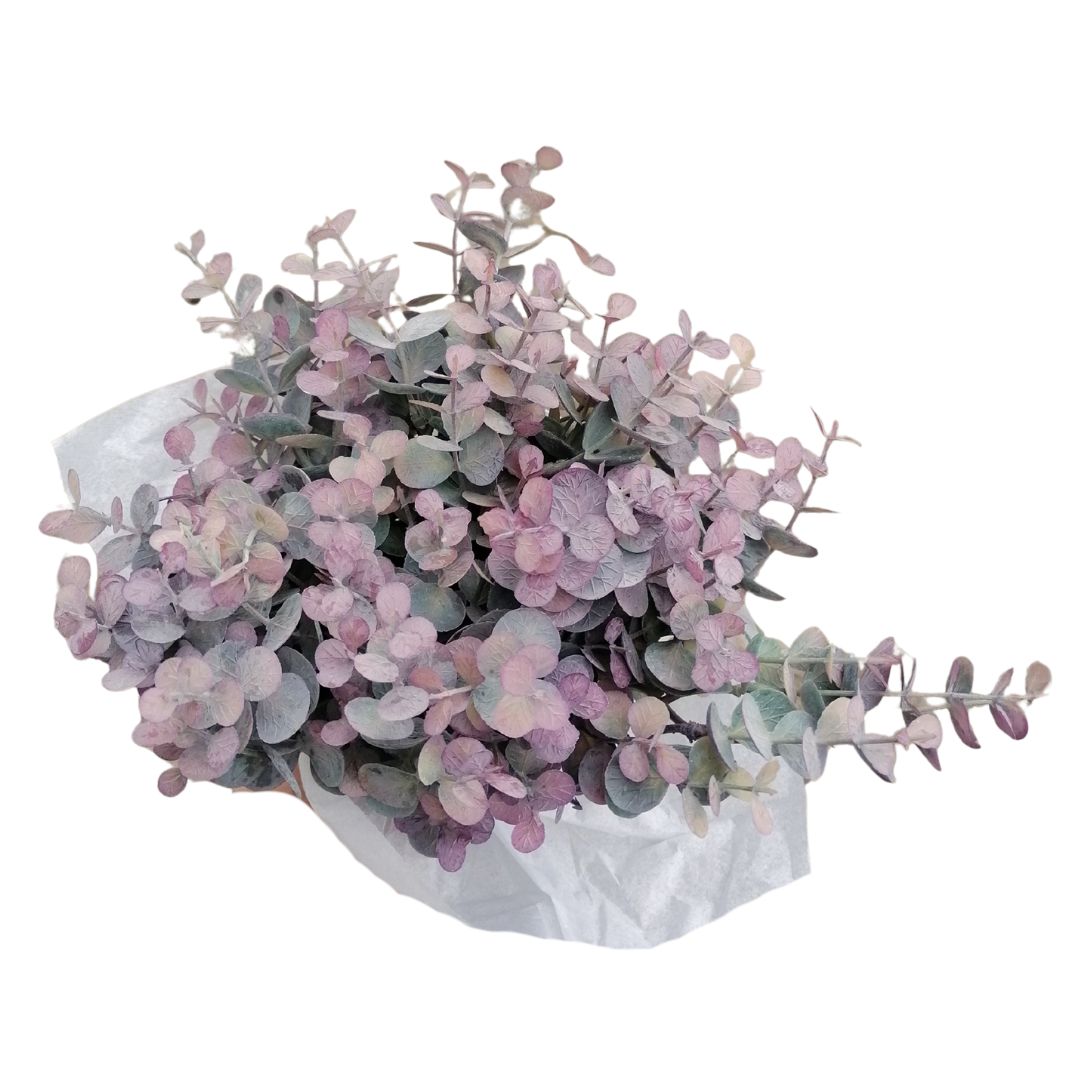 Bouquet of purple green artificial foliage in a tissue paper wrapping on a white background