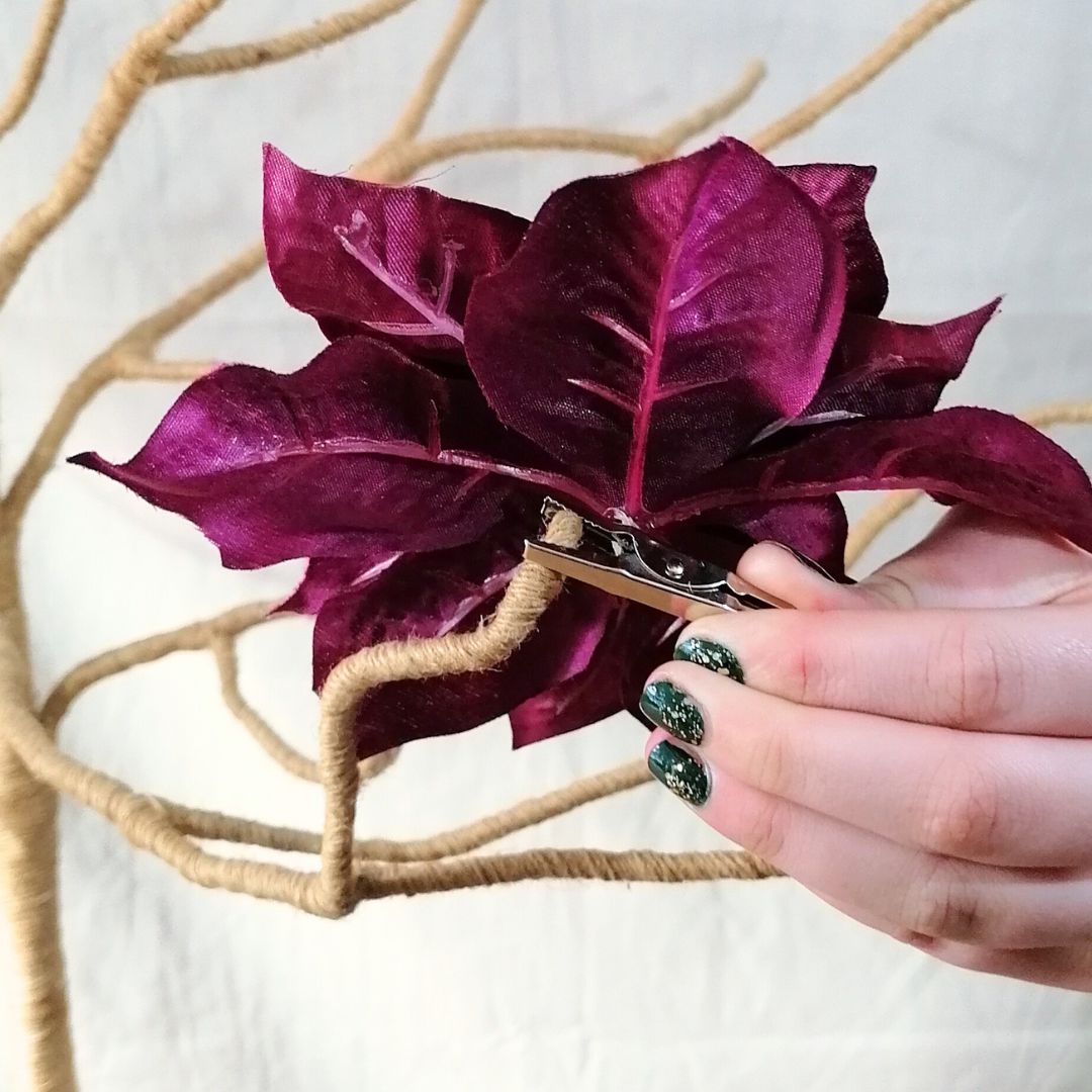 Showing the underside of the purple silk poinsettia clip on decoration being attached to a branch tree