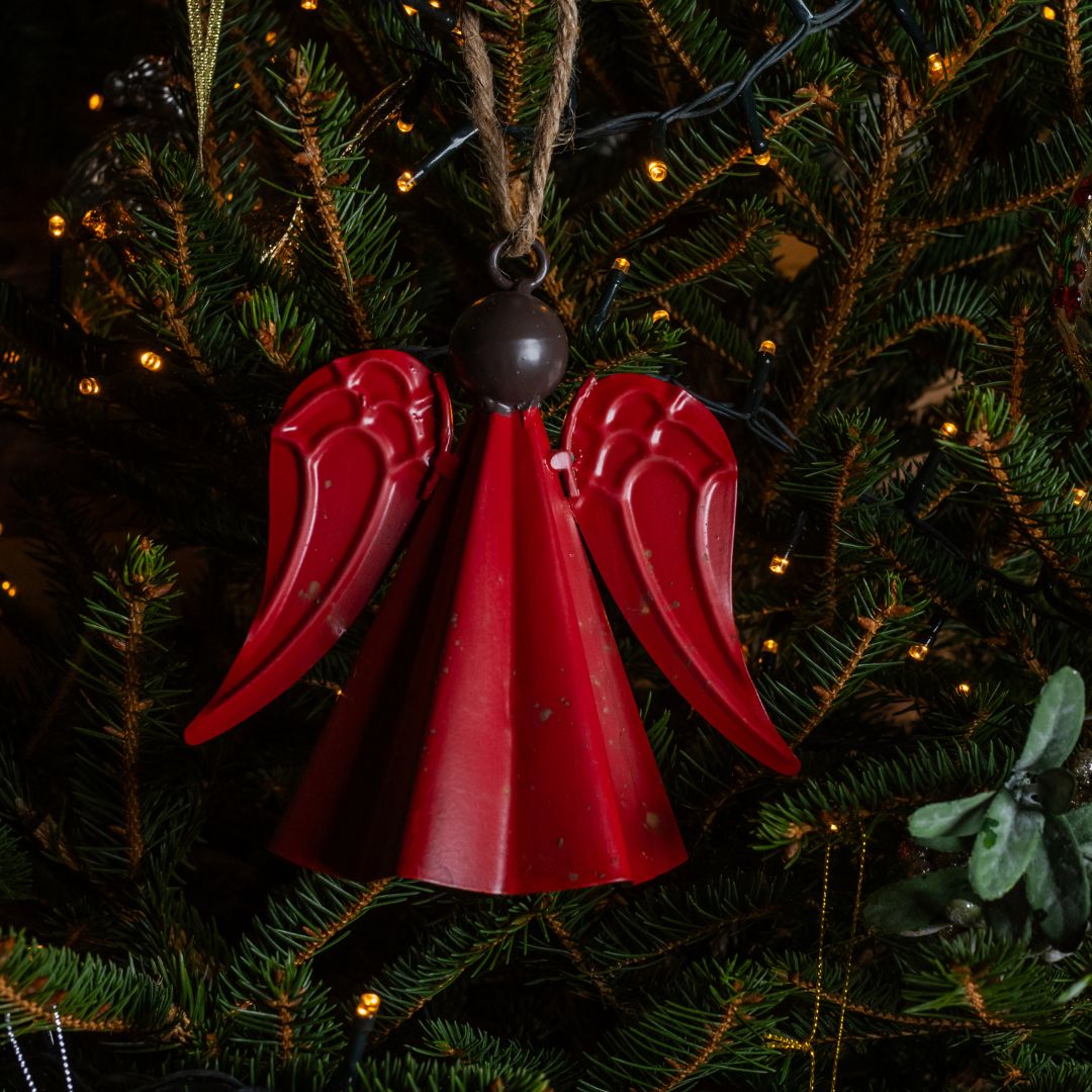Red bell ornament on a Christmas tree with lights