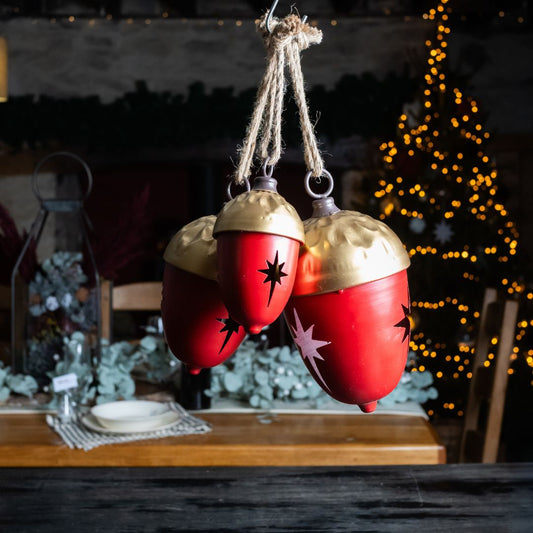 Set of 3 Red and Gold Metal Acorn Bell Hanging Decorations against a Christmas background