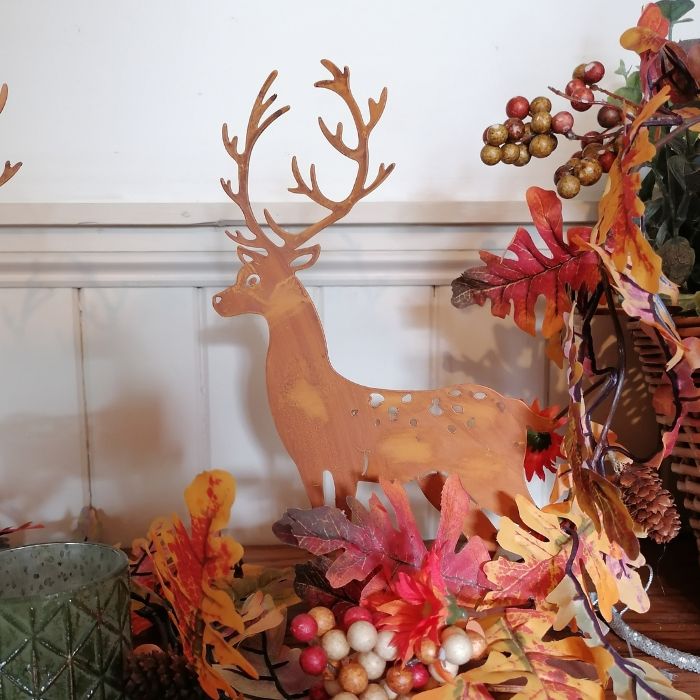 Decorative deer figure with autumn leaves and berries on a white wall background