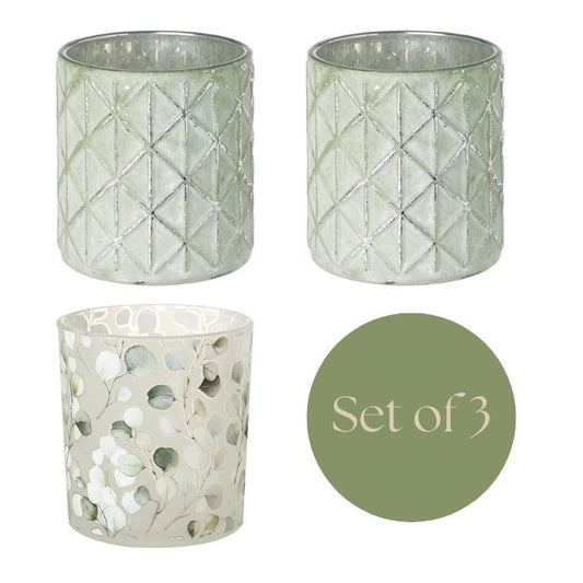 Three decorative candle holders with geometric and natural patterns on a white background.