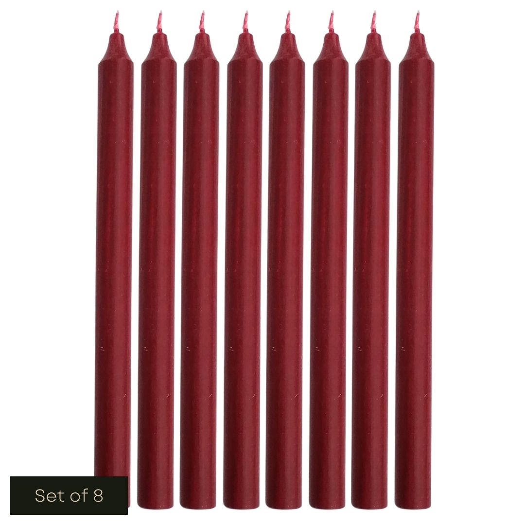 White cut out product image showing a line of 8 burgundy, fragrance-free wax dinner candles