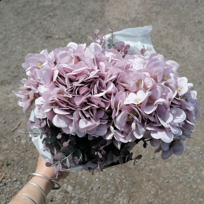 Bouquet of lilac purple flowers held by a person against a concrete background